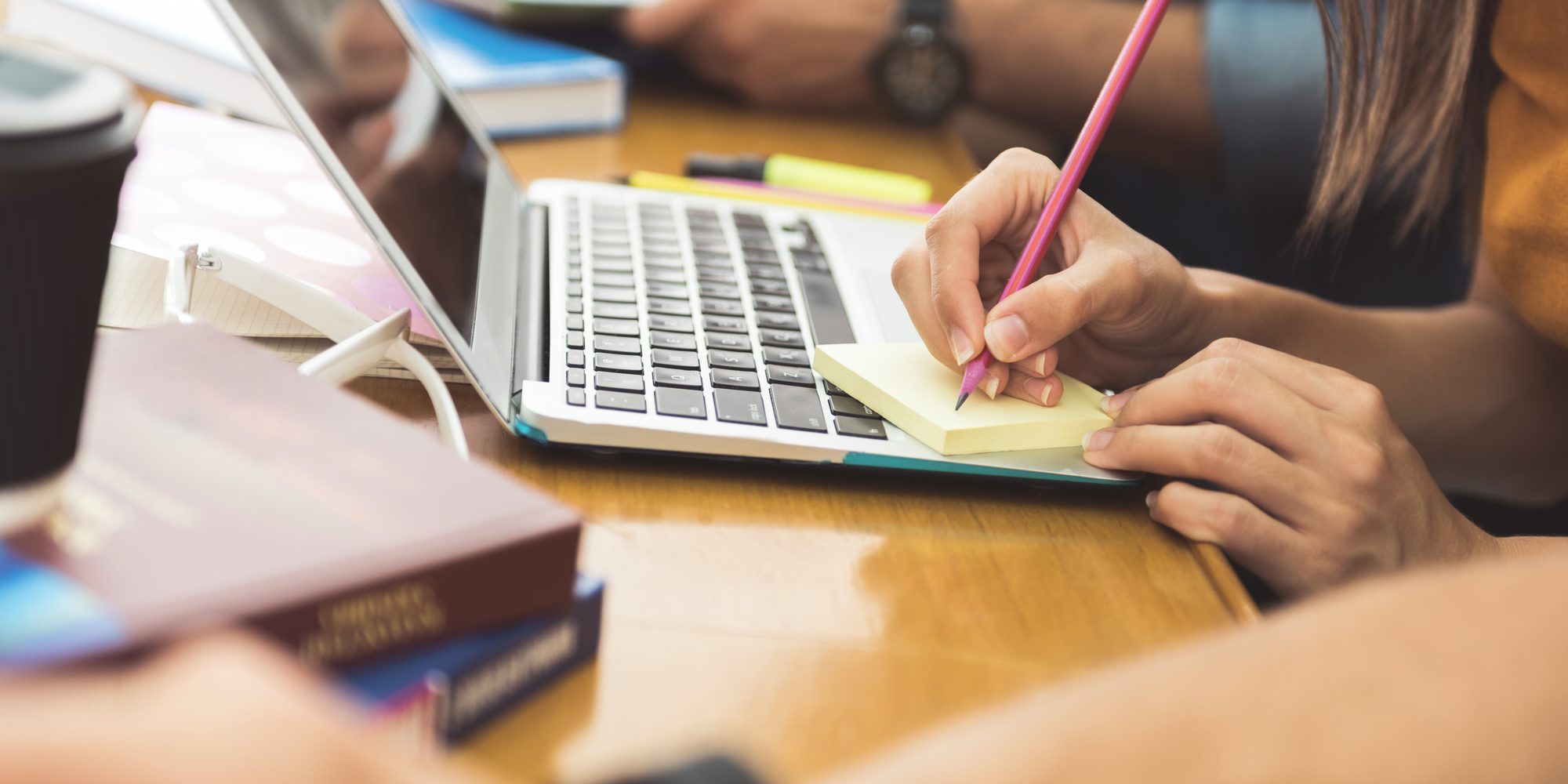 Young student writing on small paper during lecture