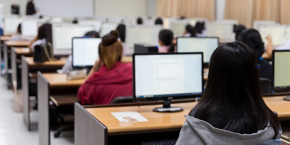 Blur and selective focus of the university student using computer studying in computer room. Group of students in study in computers room. Serious students working on computer at university.